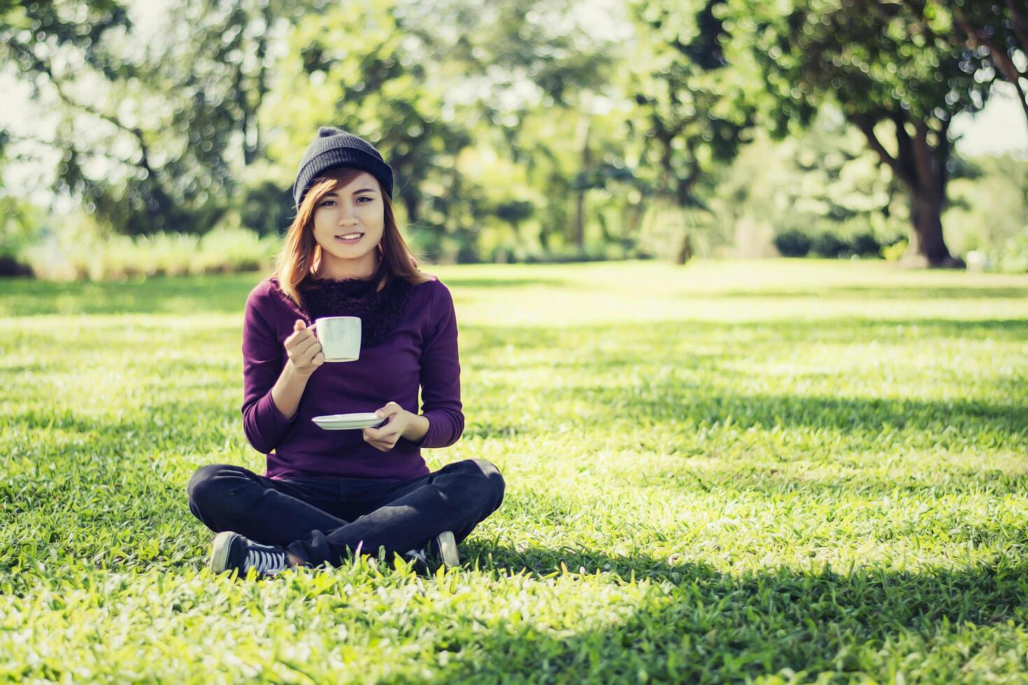 bella donna che tiene tazza di caffè e sorridente nel parco foto