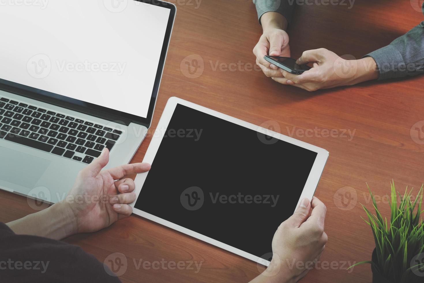 vista dall'alto di due colleghi che discutono di dati con schermo vuoto nuovo computer portatile moderno e tablet digitale professionale su scrivania in legno come concetto foto