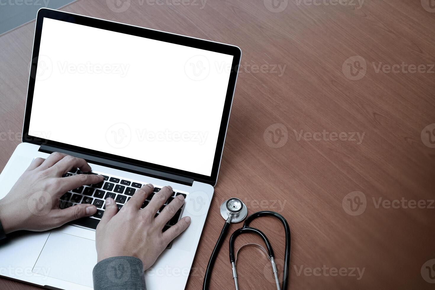 vista dall'alto della mano del medico di medicina che lavora con il computer moderno e lo schermo vuoto sulla scrivania di legno come concetto medico foto