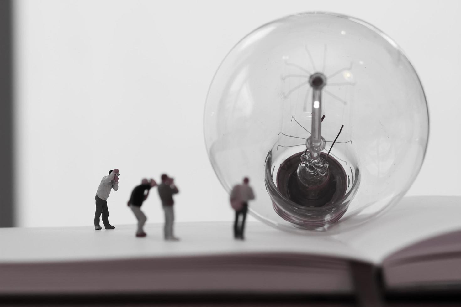 concetto di idea creativa - fotografo in miniatura con lampadina vintage su quaderno di carta aperto foto