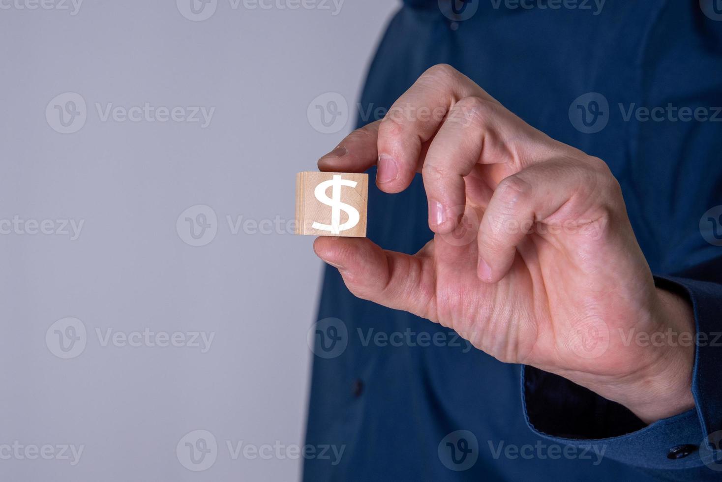 uomo d'affari mostra un cubo di legno con il simbolo del dollaro. foto