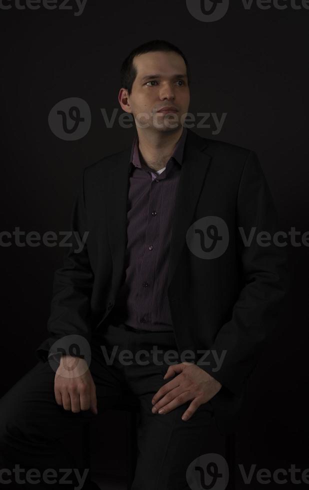 un uomo vestito di nero su sfondo nero. foto