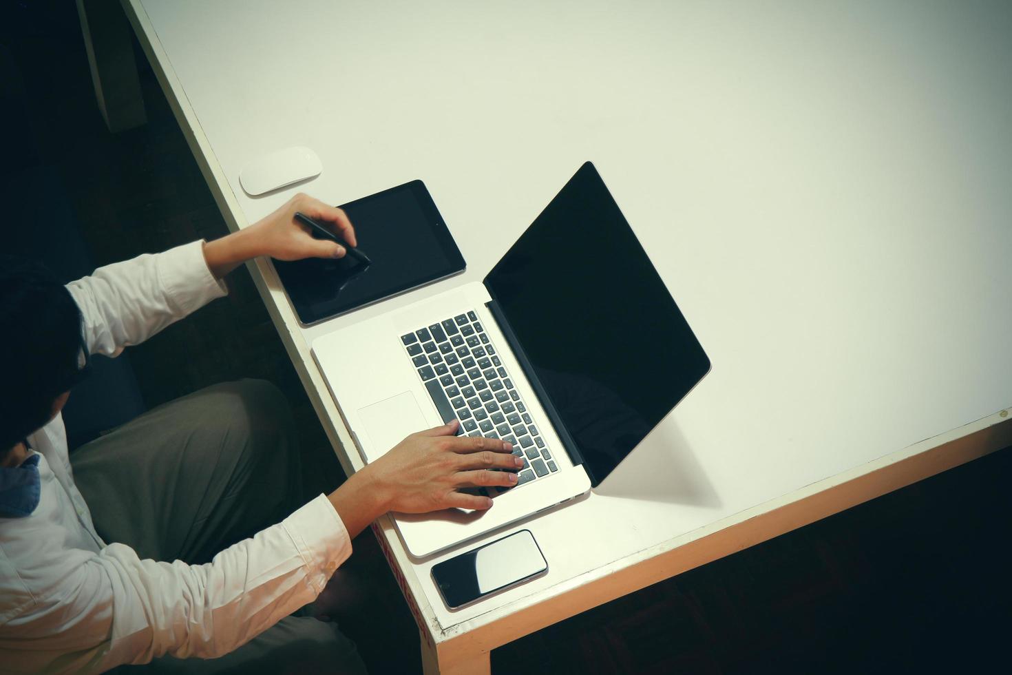 vista dall'alto dell'uomo che lavora con documenti aziendali sul tavolo dell'ufficio con tablet digitale e uomo che lavora con un computer portatile intelligente foto