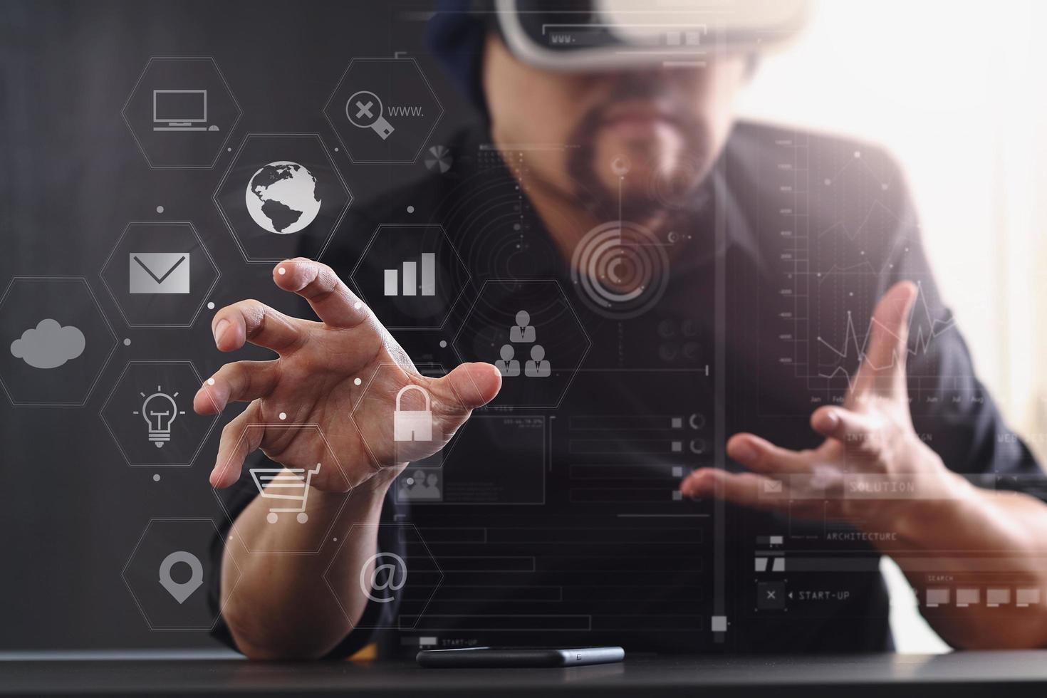 uomo d'affari che indossa occhiali per realtà virtuale in un ufficio moderno con telefono cellulare utilizzando con auricolare vr con diagramma icona dello schermo foto