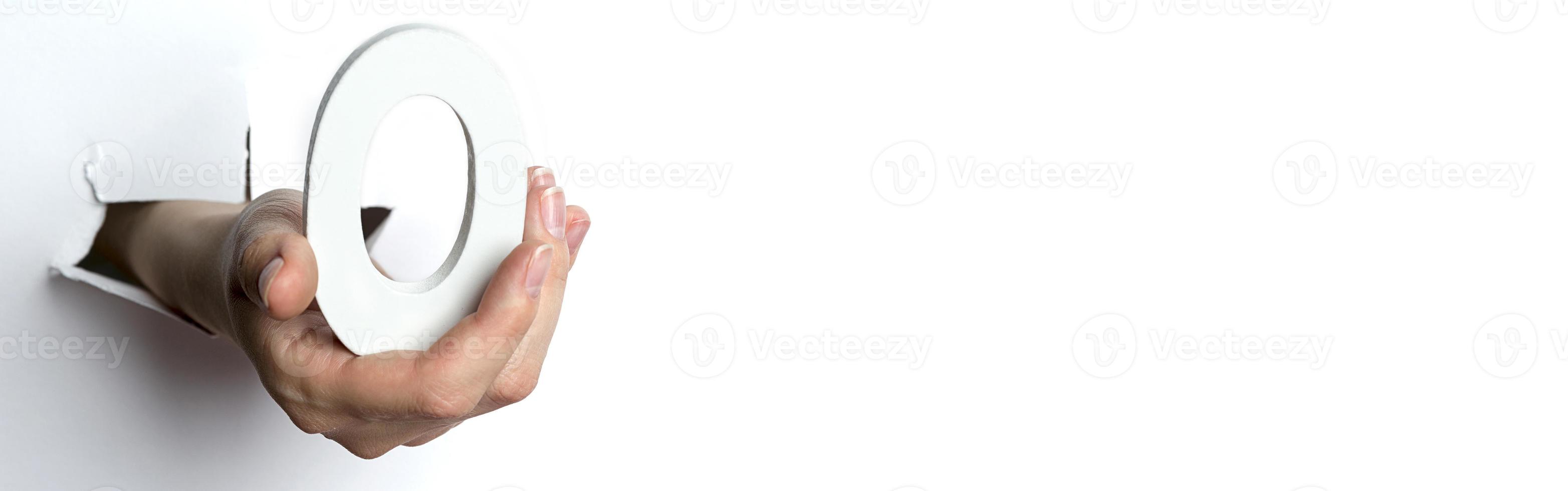 mano femminile che tiene un numero zero su sfondo bianco. copia spazio. foto