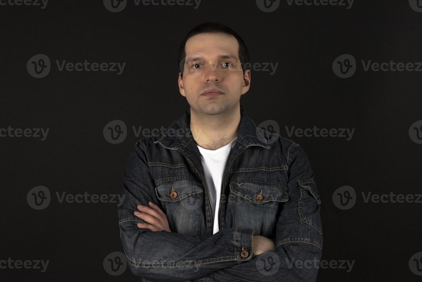 un uomo con una giacca di jeans su sfondo nero. foto