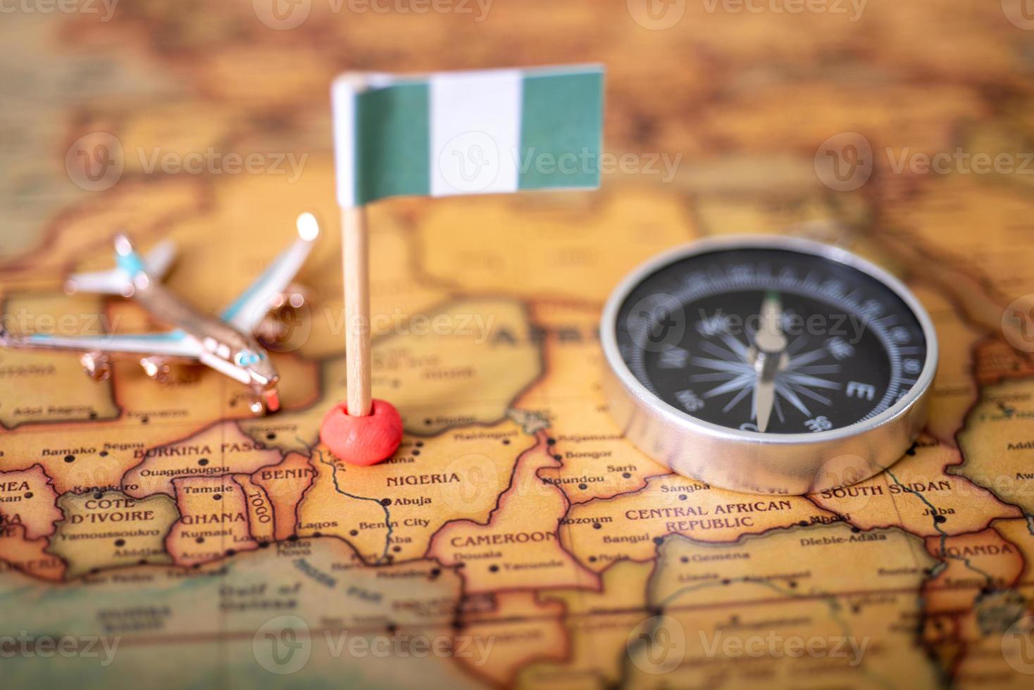 la bandiera della nigeria, un aeroplano e una bussola sulla mappa del mondo. foto
