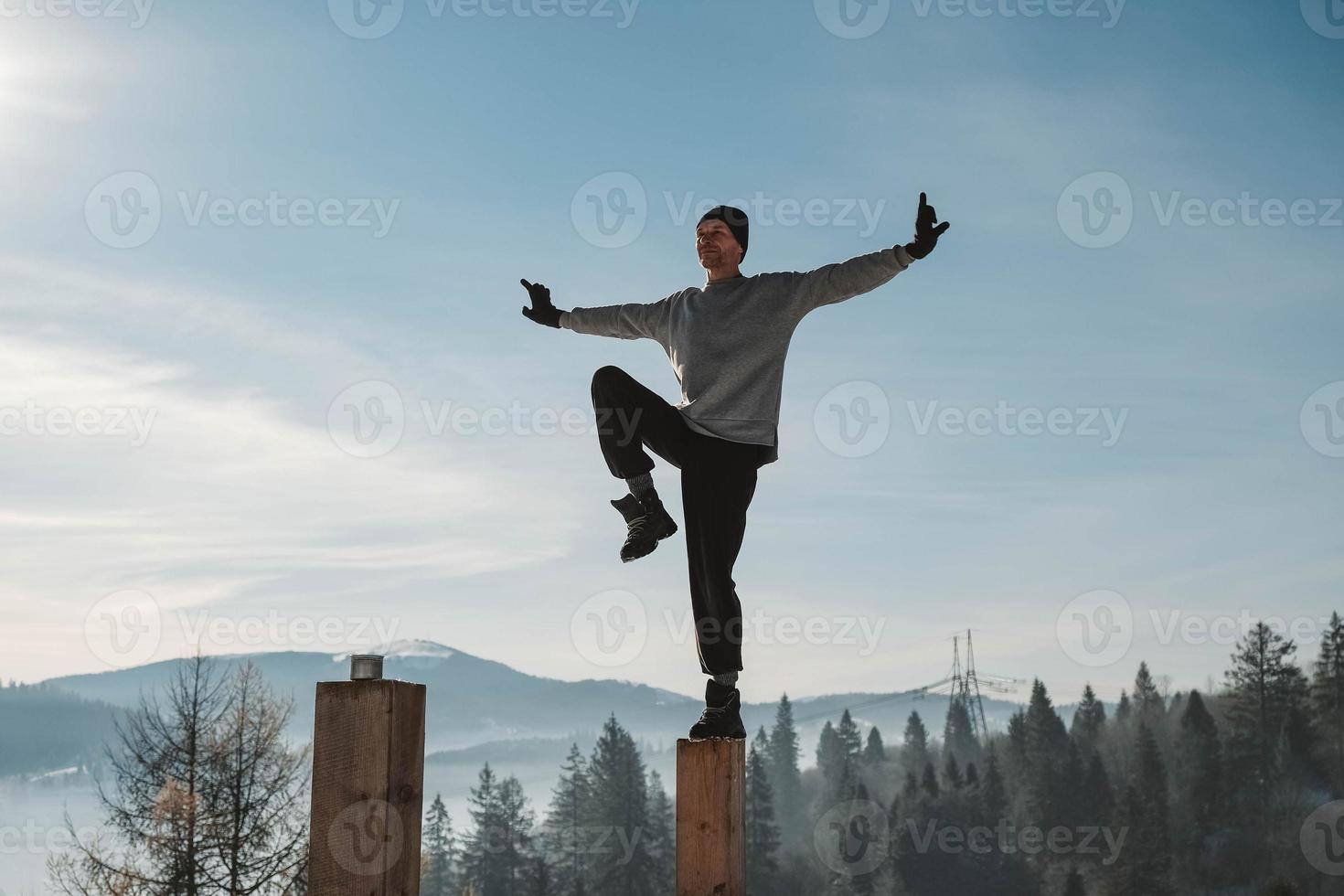 uomo che pratica yoga ed esercizi di bilanciamento nelle montagne invernali e si gode la vita. copia, spazio vuoto per il testo foto