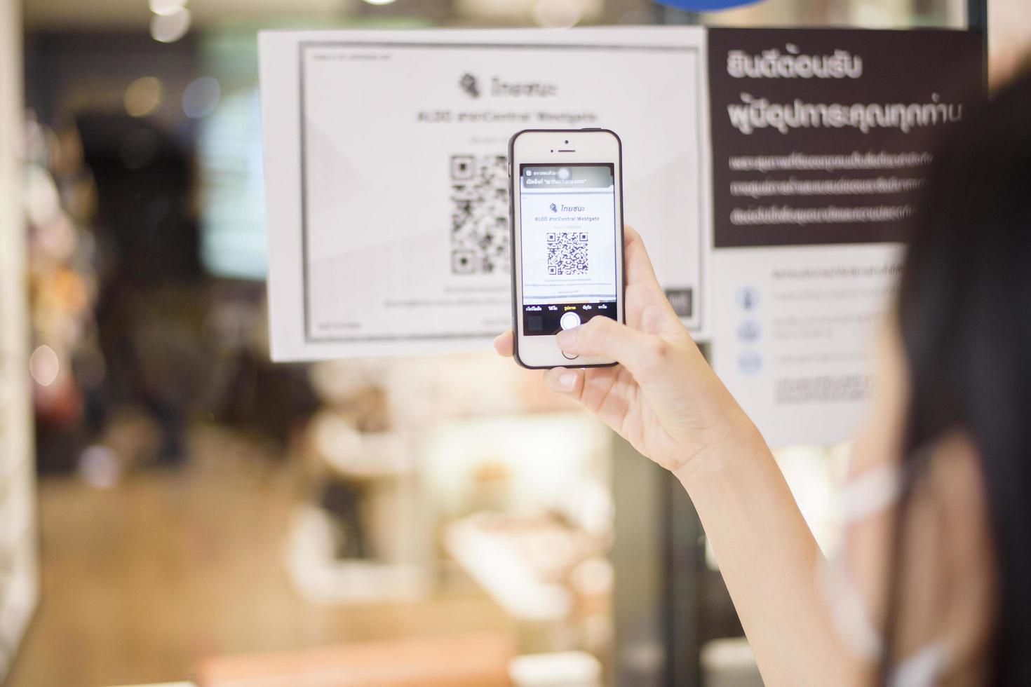 bangkok, tailandia - 17 luglio 2020 della mano della gente sta tenendo lo smartphone con la campagna thaichana della tailandia per la prevenzione del covid-19 nel centro commerciale foto