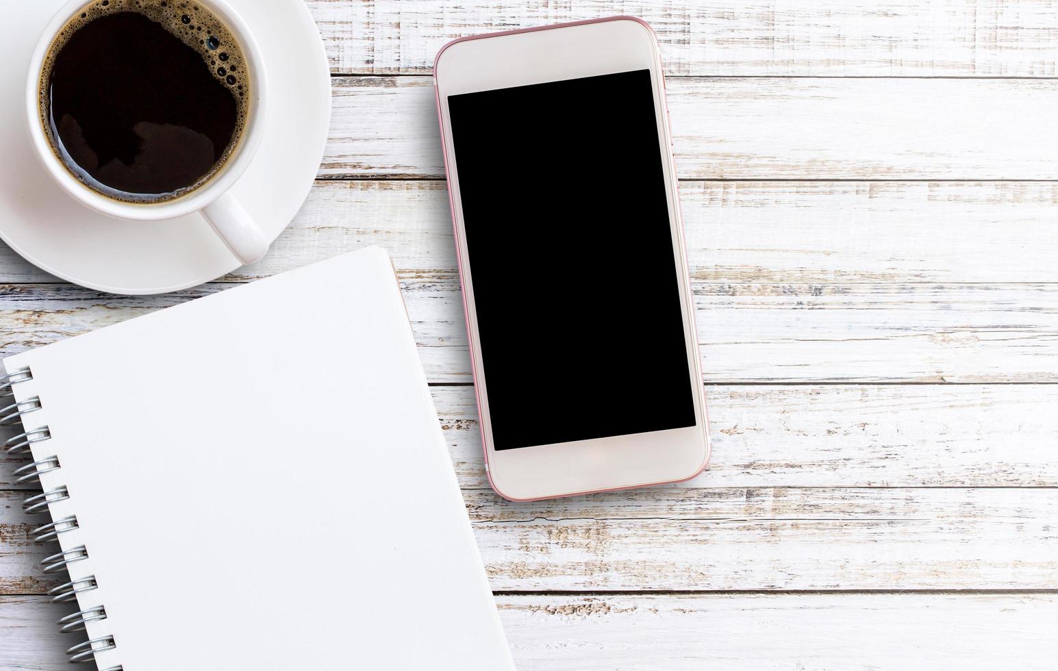 smartphone con taccuino e tazza di caffè foto