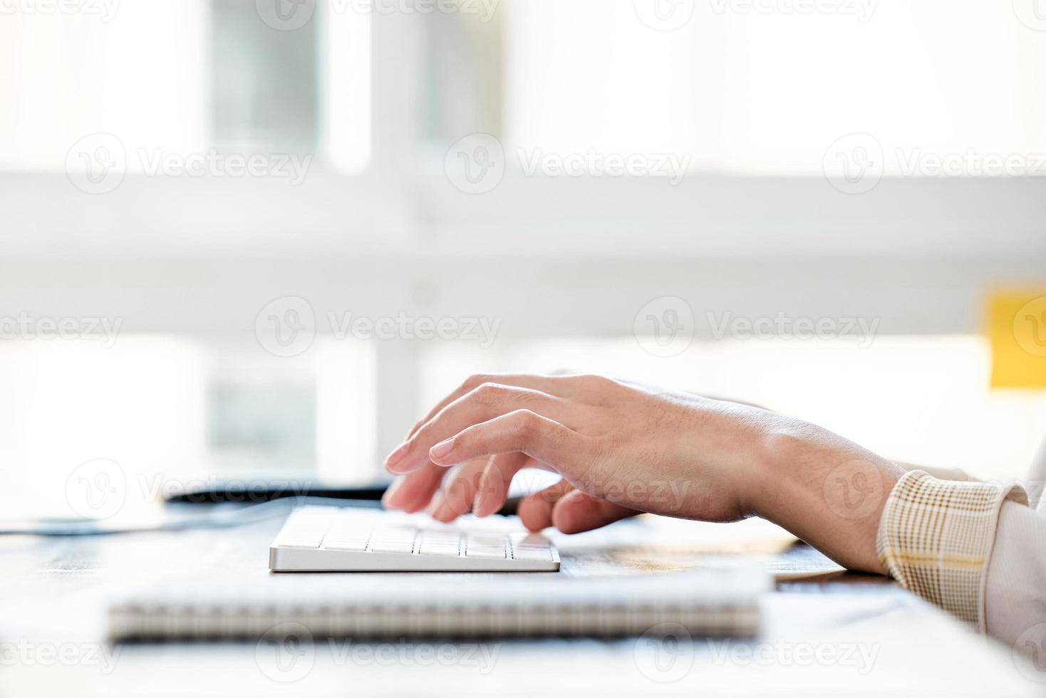 mani della donna che digitano sulla tastiera del computer sul tavolo foto