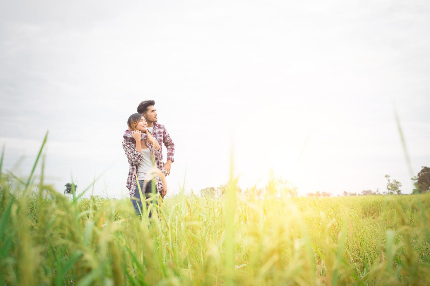 giovane coppia hipster in piedi sul campo che punta distoglie lo sguardo verso il cielo, coppia innamorata. foto