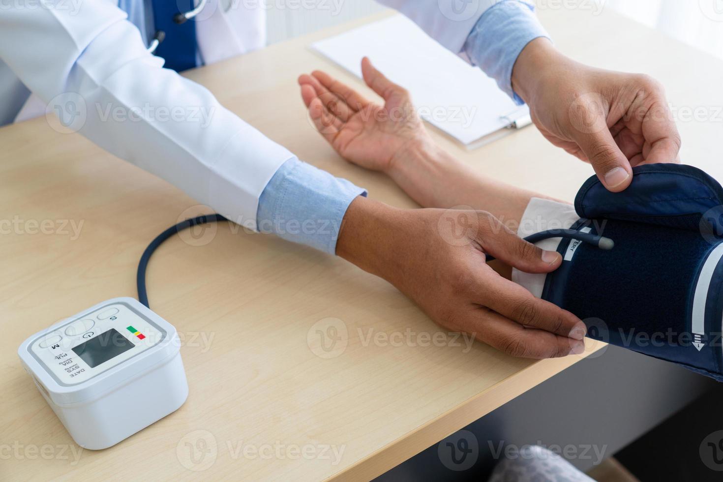medico che utilizza uno sfigmomanometro digitale automatizzato per misurare la pressione sanguigna di una paziente anziana che visita l'ospedale a causa dell'ipertensione foto