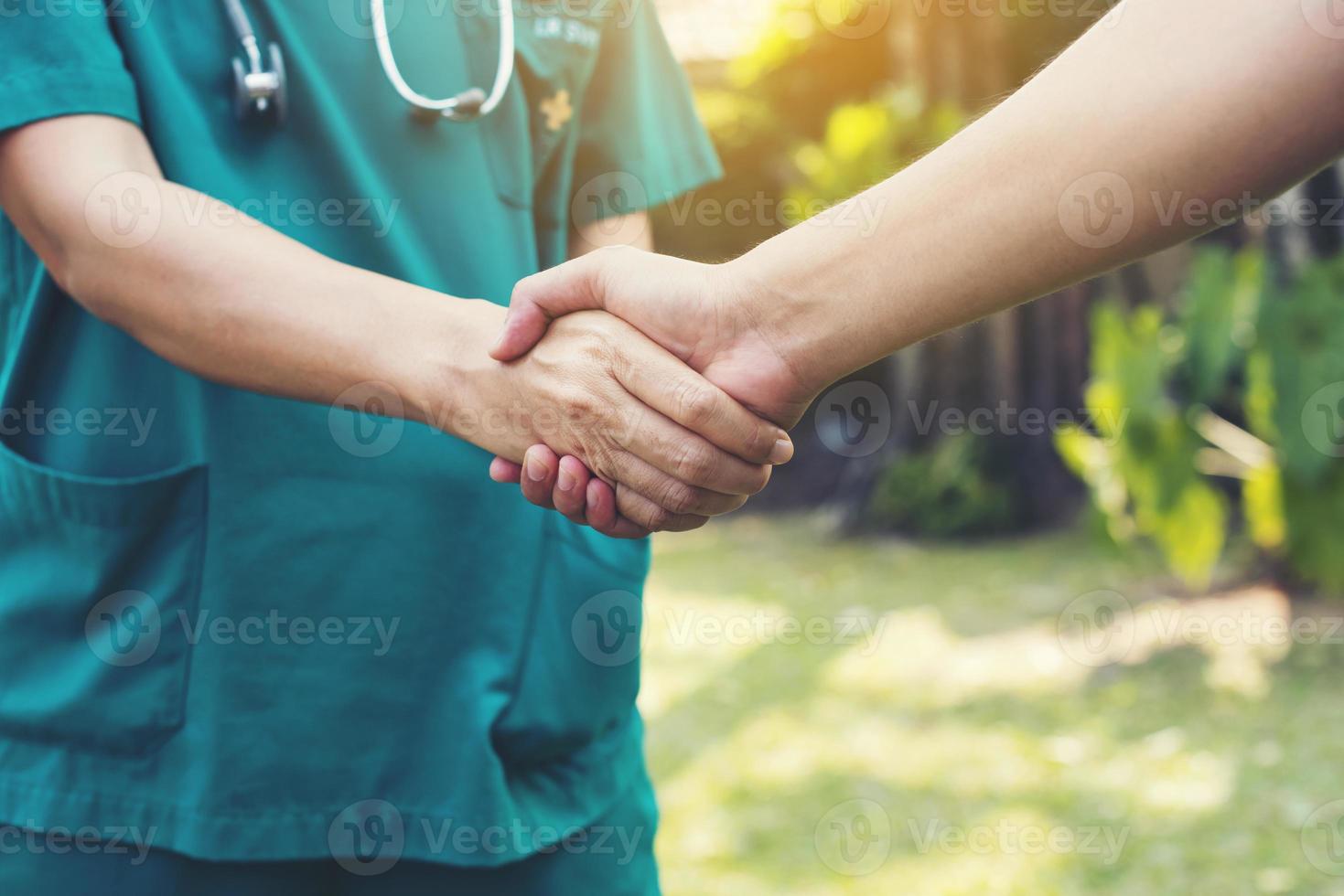 stretta di mano tra il panno verde del medico e il paziente foto