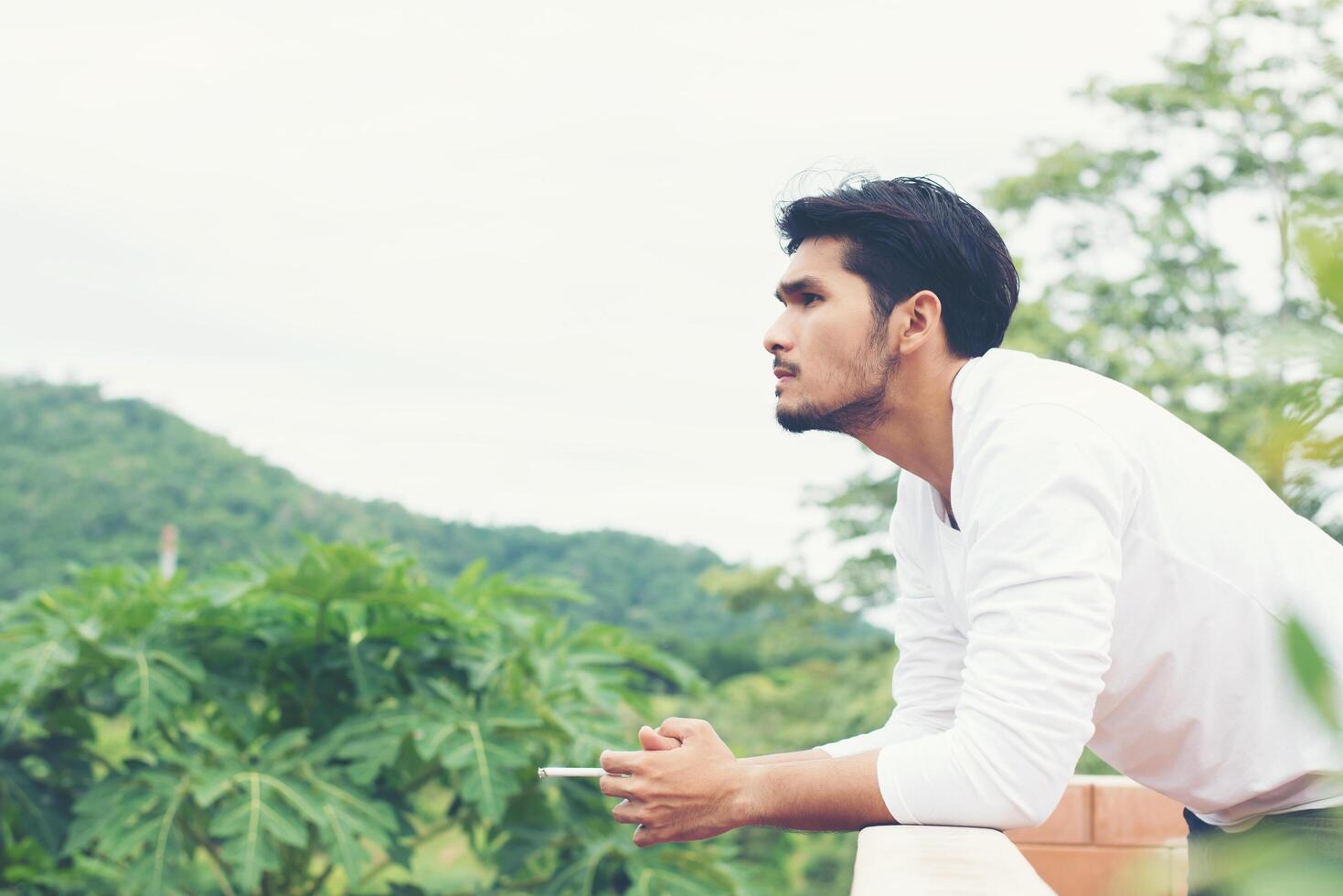 giovane uomo hipster che si riposa, fuma sigaretta con la natura e la brezza fresca. foto