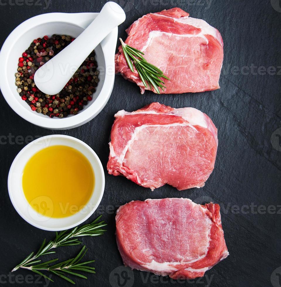 braciole di maiale fresche crude con spezie ed erbe aromatiche foto