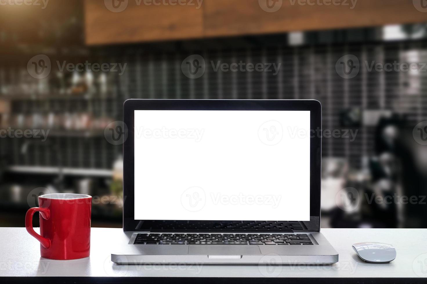 vista frontale di tazza e laptop, smartphone e tablet sul tavolo in ufficio e sfondo nella caffetteria e nel ristorante foto