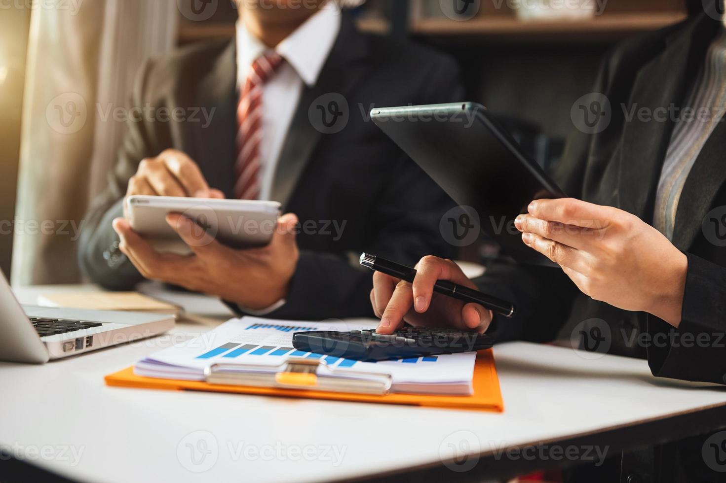 documenti aziendali sul tavolo dell'ufficio con smartphone e calcolatrice tavoletta digitale e grafico aziendale con diagramma di rete sociale e due colleghi che discutono di lavoro sui dati foto