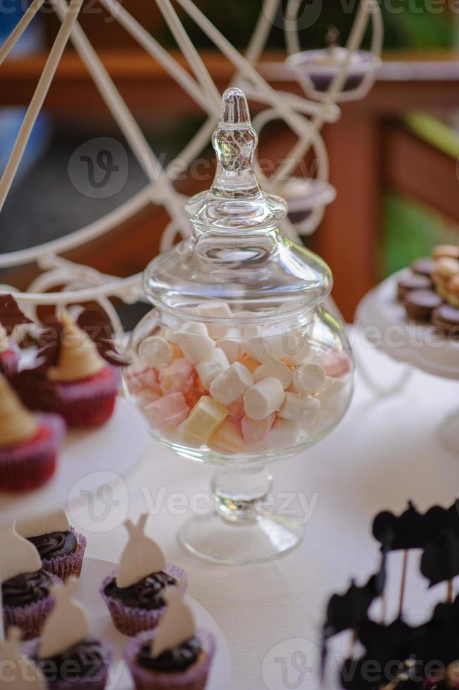 primo piano del vassoio con molte deliziose torte di pasticceria tortine e amaretti di fila. dolci freschi, multicolori, colorati, verdi, gialli, bianchi e rosa ai frutti di bosco, splendidamente decorati foto