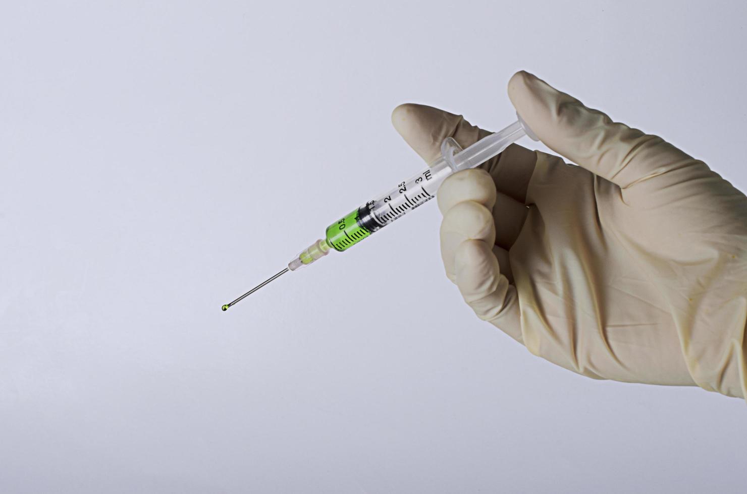 mano che tiene una siringa per il vaccino antivirus per il concetto di medicina su sfondo grigio foto