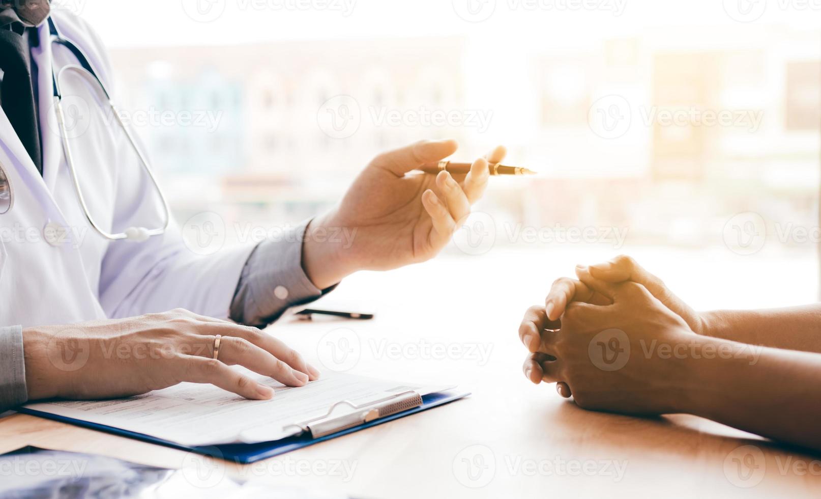 mano del medico che tiene la penna e parla con il paziente di farmaci e cure. foto