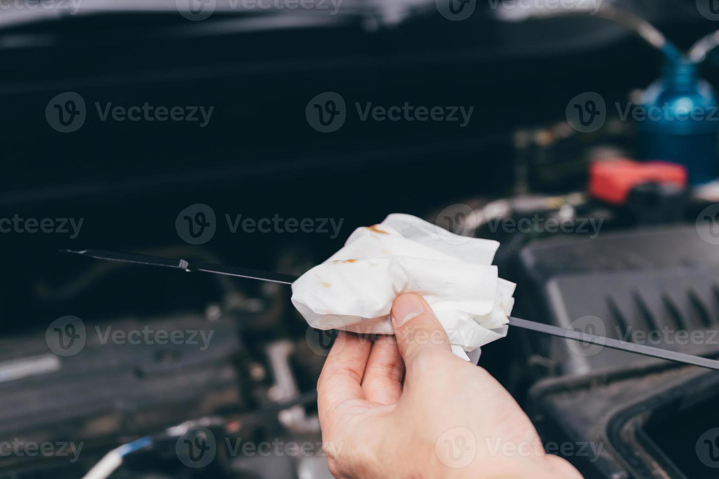 il meccanico di auto sta controllando l'olio motore dell'auto usando un acciaio e un detergente per tessuto. foto
