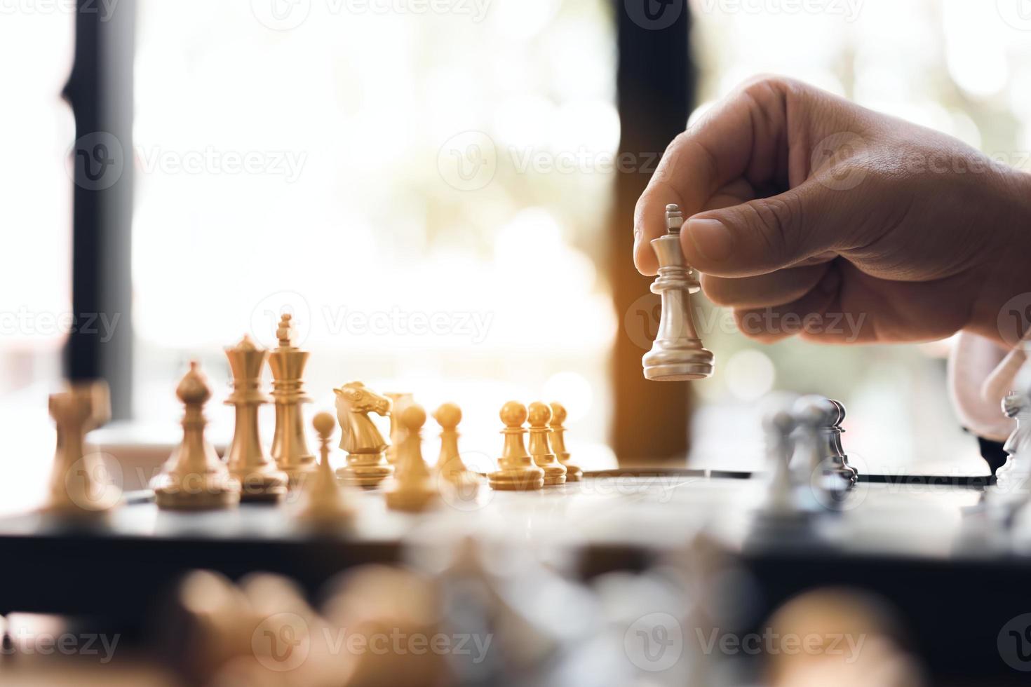 Chiuda sulla mano dell'uomo d'affari che muove il re in una partita di scacchi per vincere. foto