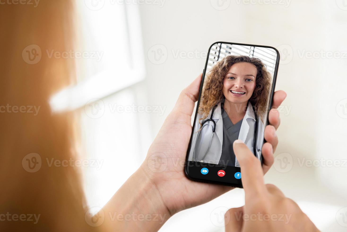 paziente che effettua una videochiamata con il medico online tramite telefono cellulare, servizio di consulenza medica a domicilio e concetti di telemedicina foto