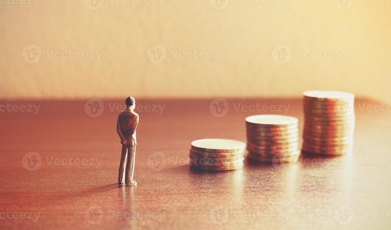 persone in miniatura che guardano al futuro con una pila di monete sul concetto di risparmio finanziario e di denaro. foto