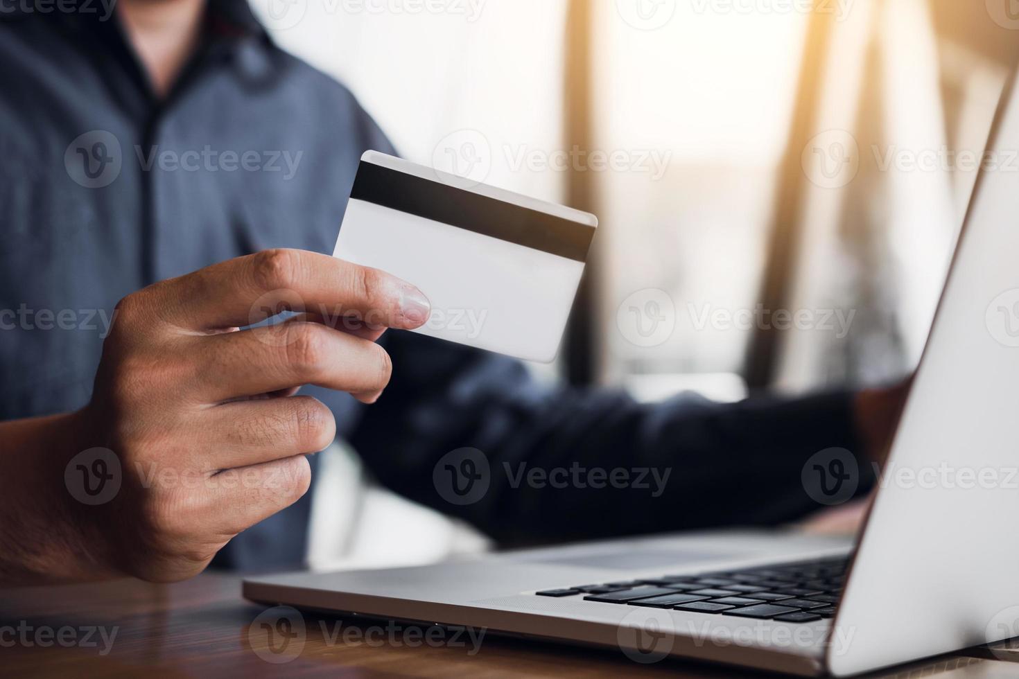 concetto di shopping online con la mano dell'uomo utilizzando il laptop e cercando la carta di credito per il prodotto dell'ordine di acquisto. foto