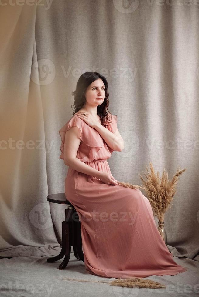 donna in un vestito rosa su uno sfondo di tessuto di lino foto