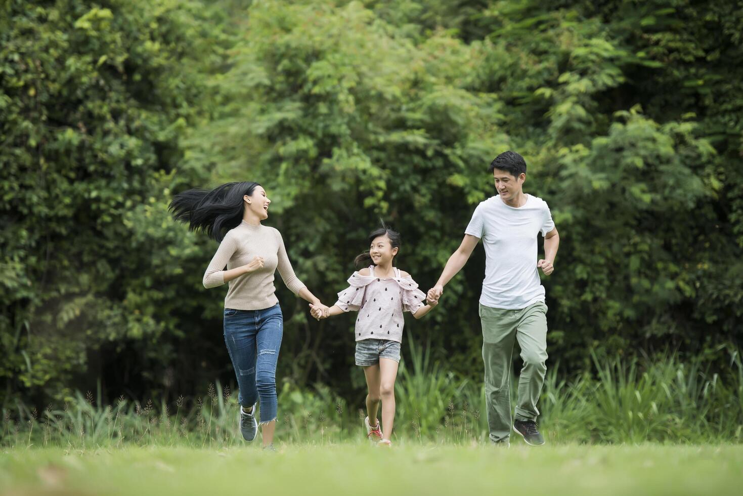 la famiglia felice si diverte madre, padre e figlia corrono nel parco. foto