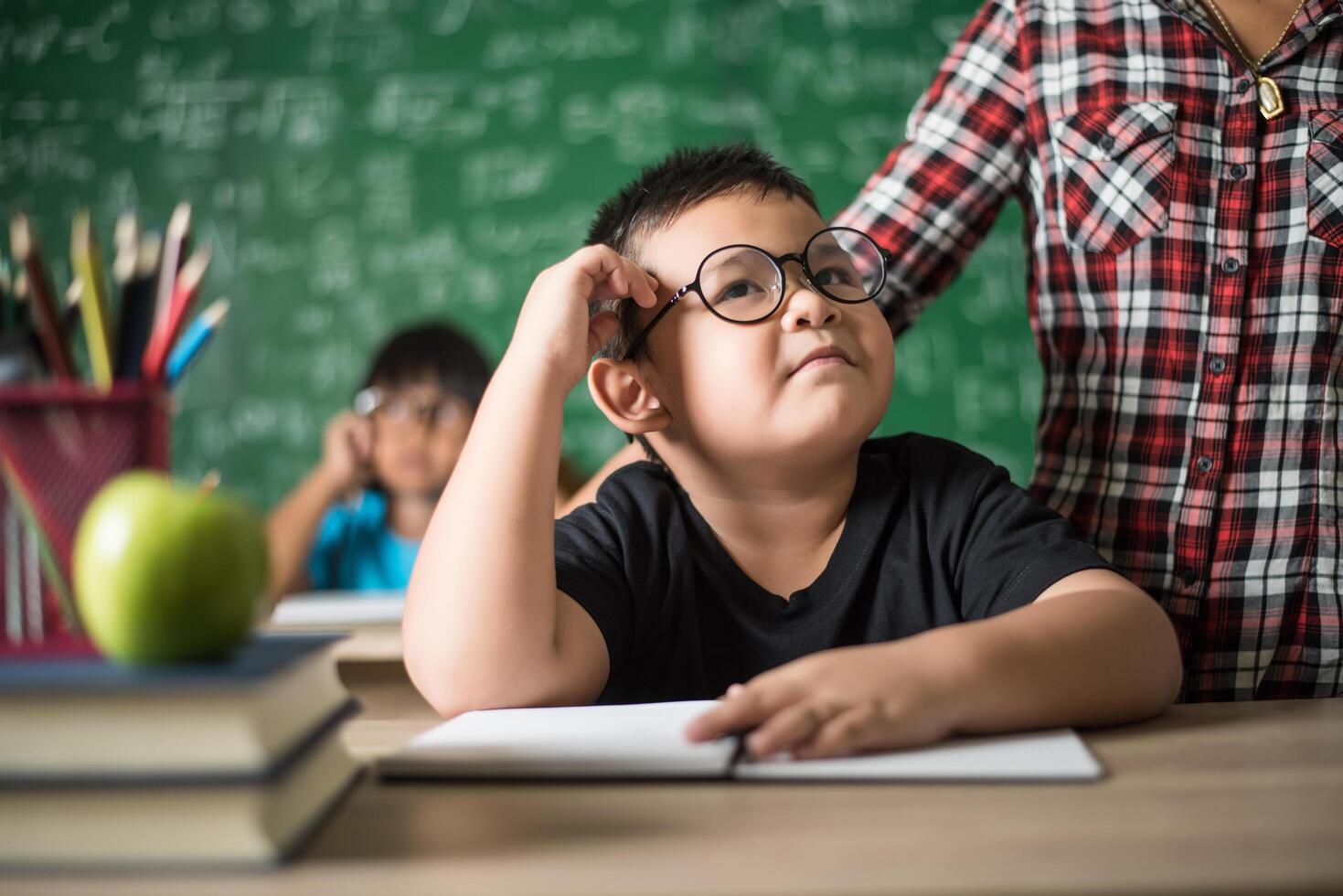 ragazzino premuroso con libro vicino a un consiglio scolastico foto