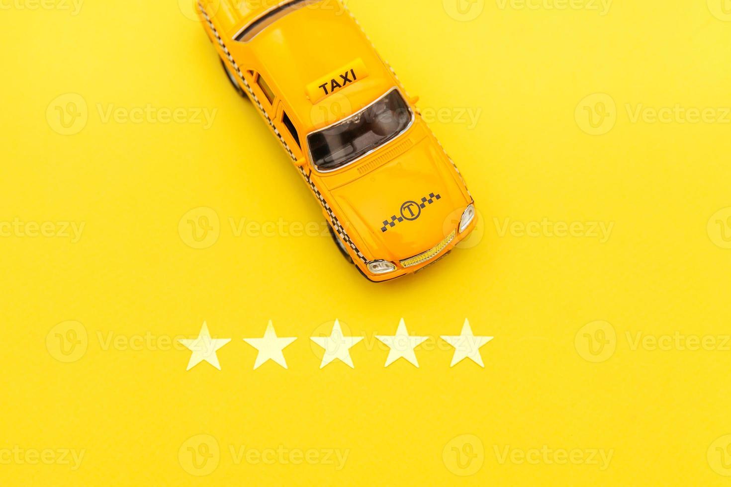taxi auto giocattolo giallo e 5 stelle isolato su sfondo giallo. applicazione per smartphone del servizio taxi per la ricerca online di chiamate e prenotazione del concetto di taxi. simbolo del taxi. copia spazio. foto
