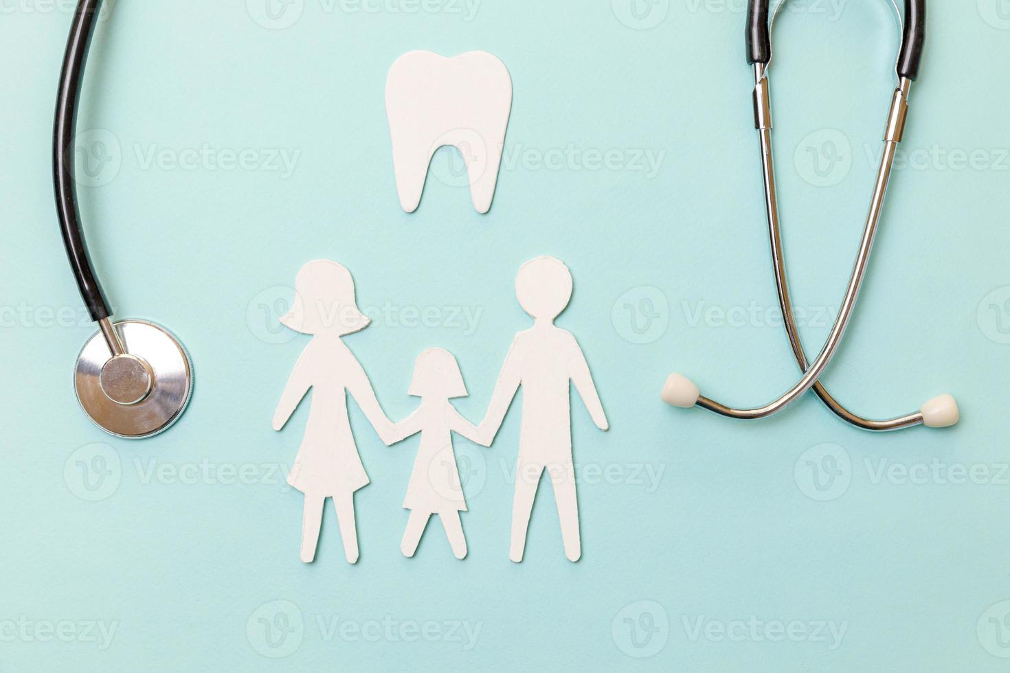 concetto di cure odontoiatriche per la salute della famiglia. stetoscopio piatto bianco dente sano modello simbolo ritaglio famiglia isolato su sfondo blu. controllo dal dentista medico bambino. giornata del dentista per l'igiene orale dentale foto