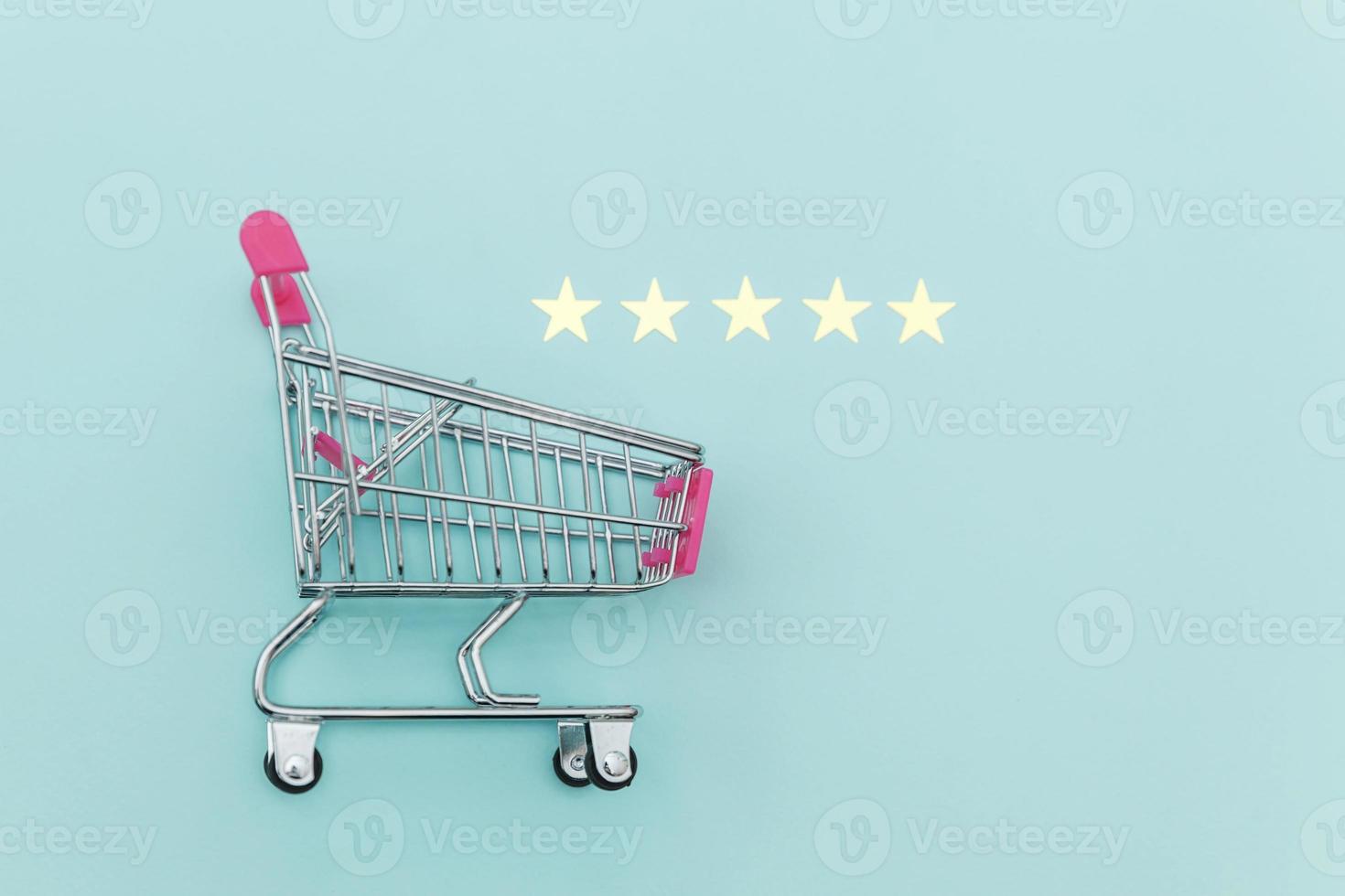 piccolo supermercato carrello per la spesa giocattolo con ruote e 5 stelle isolato su sfondo blu pastello. concetto di valutazione e revisione online dell'acquisto di consumatori al dettaglio. foto
