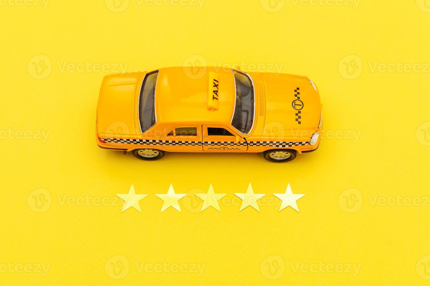 taxi auto giocattolo giallo e 5 stelle isolato su sfondo giallo. applicazione per smartphone del servizio taxi per la ricerca online di chiamate e prenotazione del concetto di taxi. simbolo del taxi. copia spazio. foto