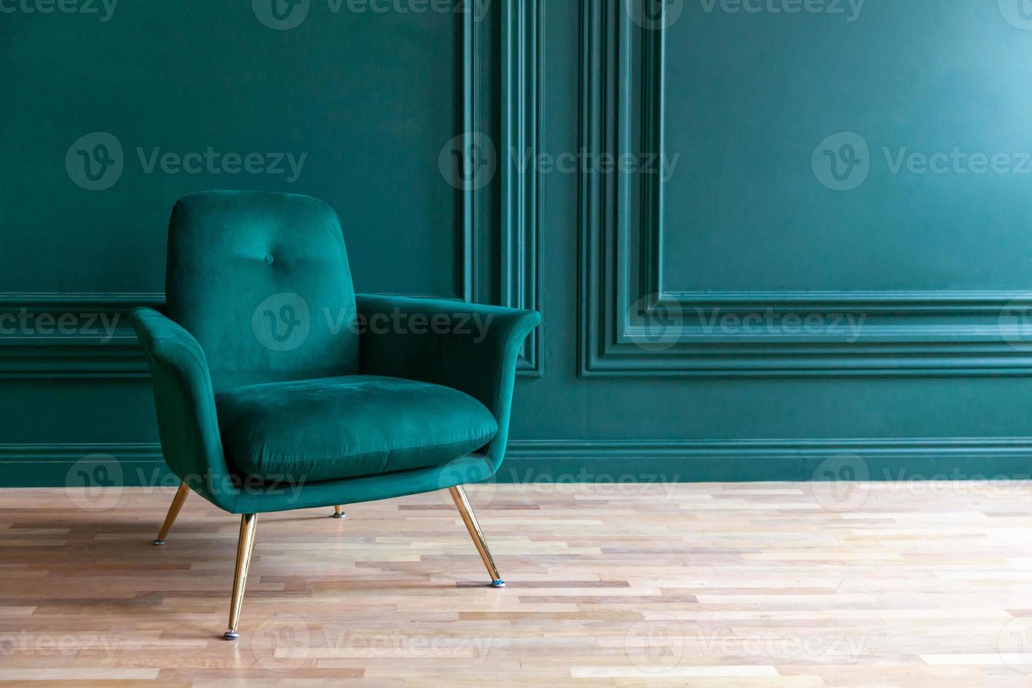 bella camera interna pulita di lusso classico blu verde in stile classico con poltrona morbida verde. sedia blu-verde antica d'epoca in piedi accanto al muro color smeraldo. design per la casa minimalista. foto