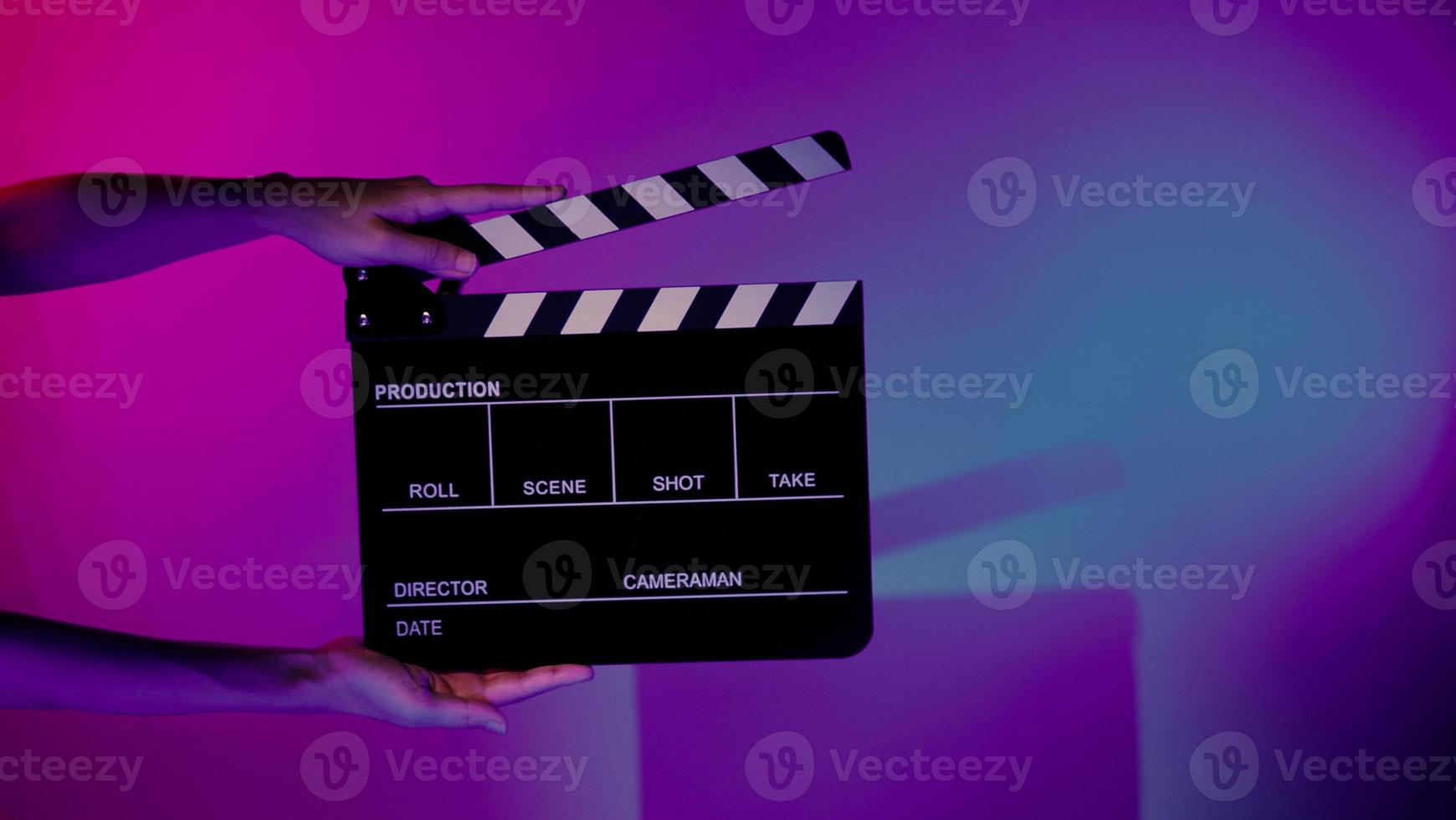 la mano tiene il ciak vuoto per la produzione di film su sfondo colorato in studio foto