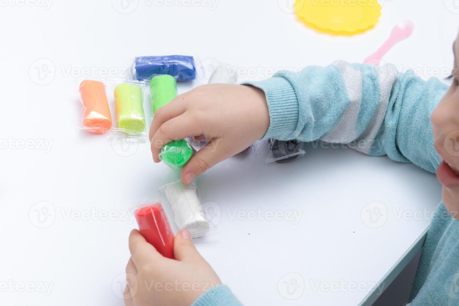 le mani dei bambini giocano la pasta per la creatività dei bambini. gioco da tavolo per lo sviluppo della motricità fine foto