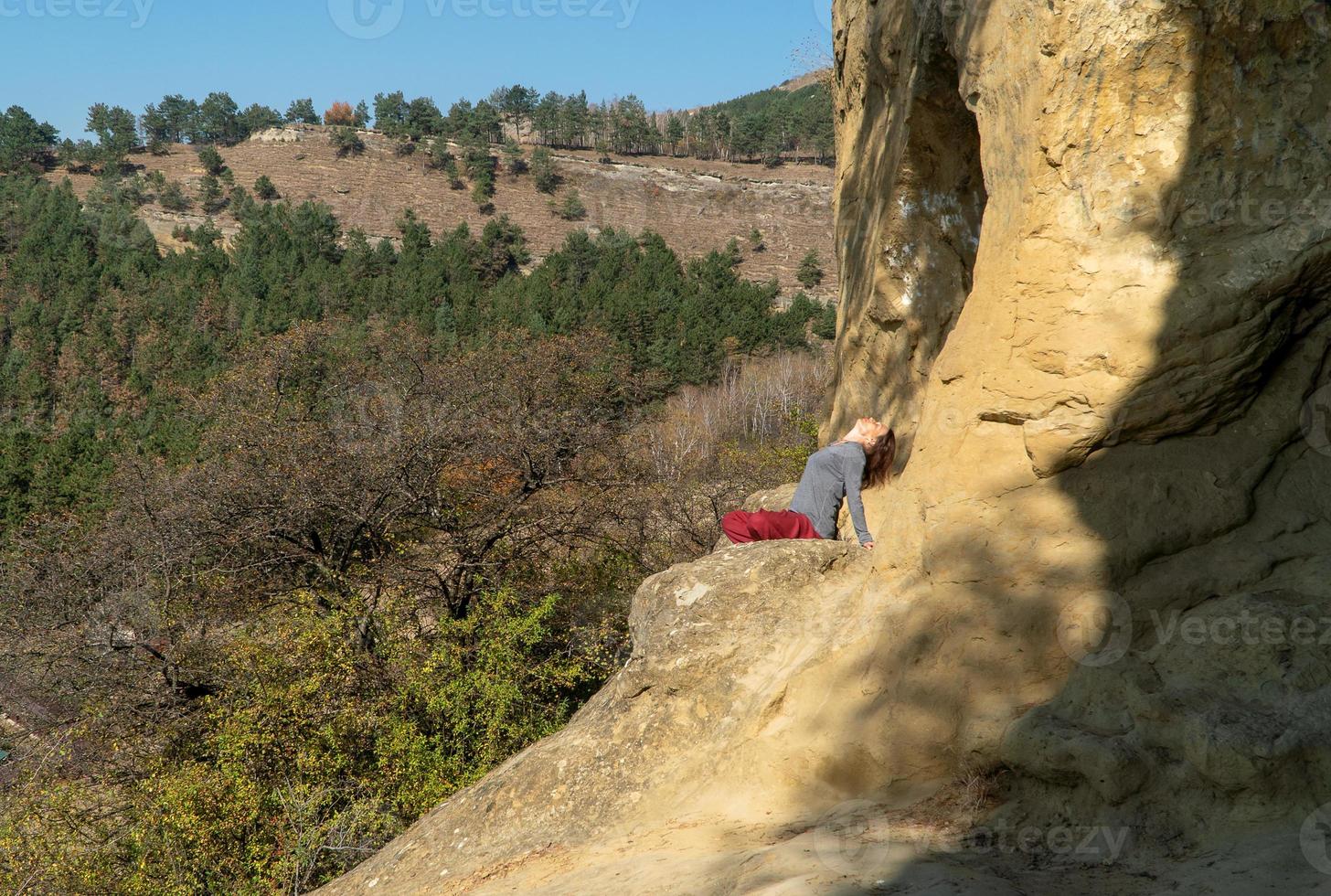 donna con gli occhi chiusi seduta su una montagna nella posizione del loto in meditazione in una giornata autunnale foto