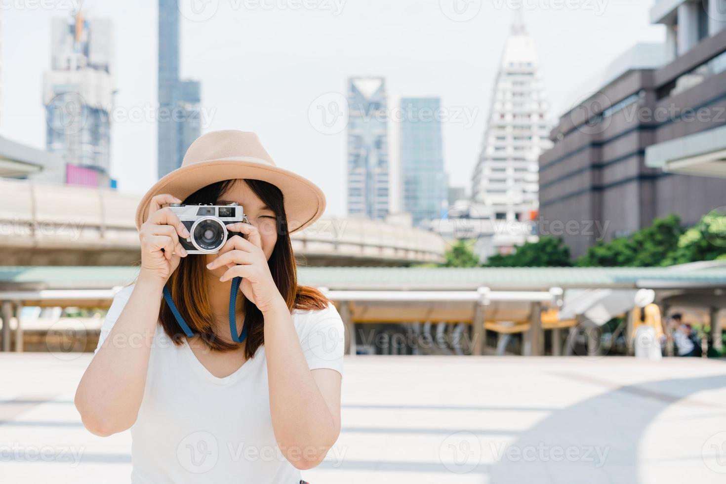 la bella donna asiatica del viaggiatore felice trasporta lo zaino. giovani donne asiatiche gioiose che usano la fotocamera per fare foto durante il tour della città, emozioni allegre, ottimo umore. stile di vita delle donne all'aperto nel concetto di città.