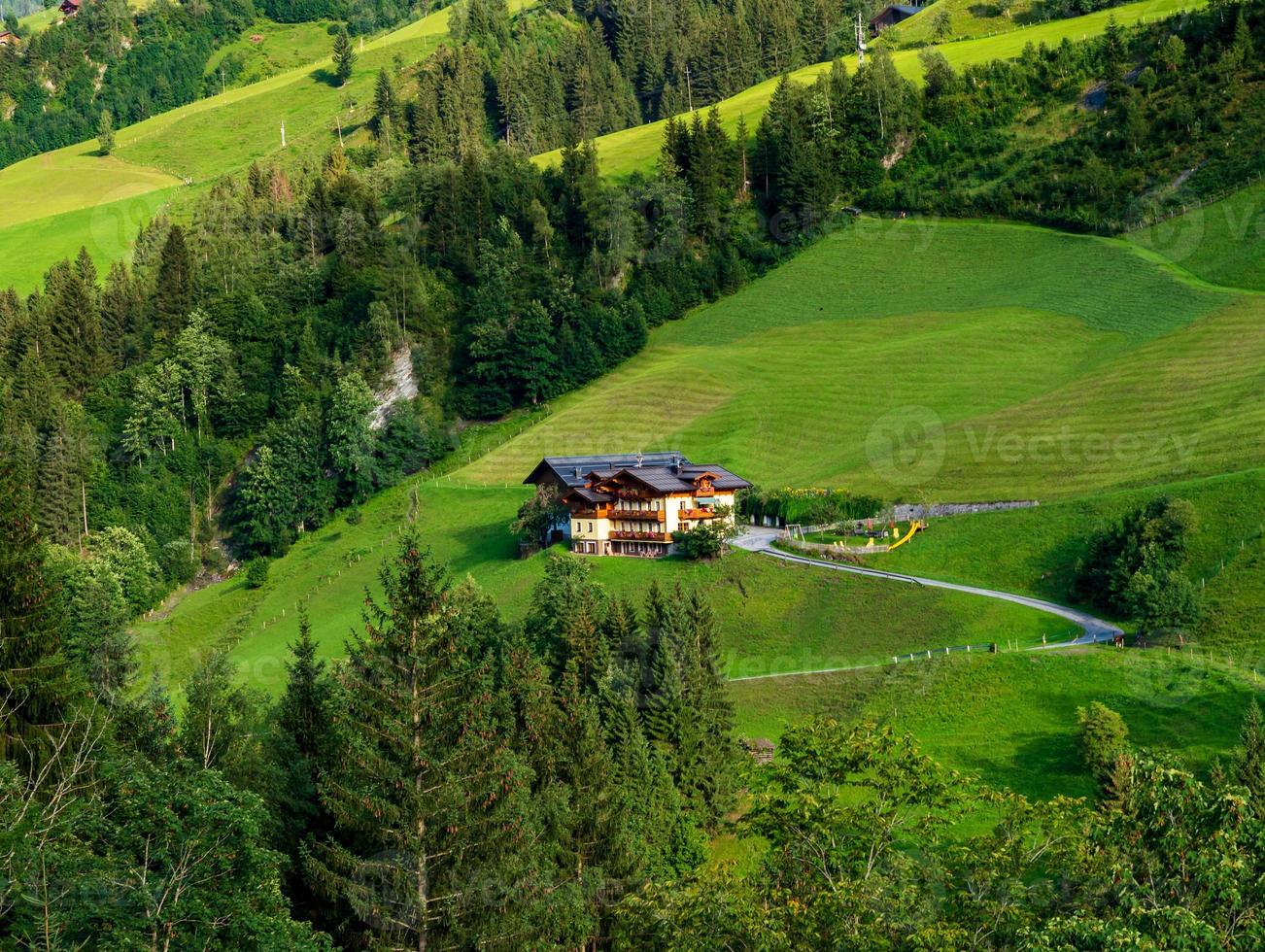 verdi colline di una località alpina in austria in estate. piccolo villaggio, hotel e chalet, tutti a colori. belle terrazze e pannelli solari sui tetti. la vicinanza della civiltà e della natura pura. foto