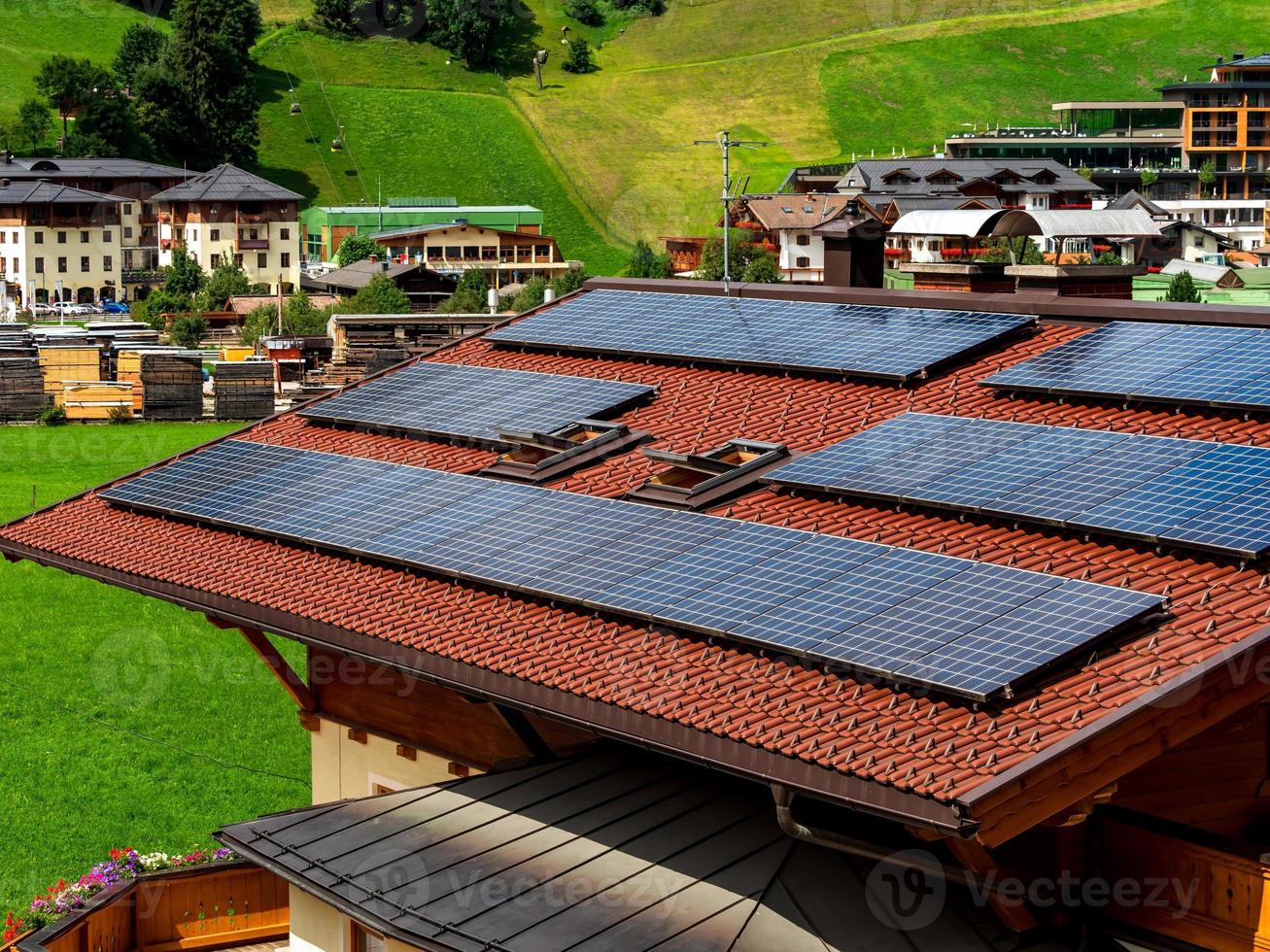 verdi colline di una località alpina in austria in estate. piccolo villaggio, hotel e chalet, tutti a colori. belle terrazze e pannelli solari sui tetti. la vicinanza della civiltà e della natura pura. foto