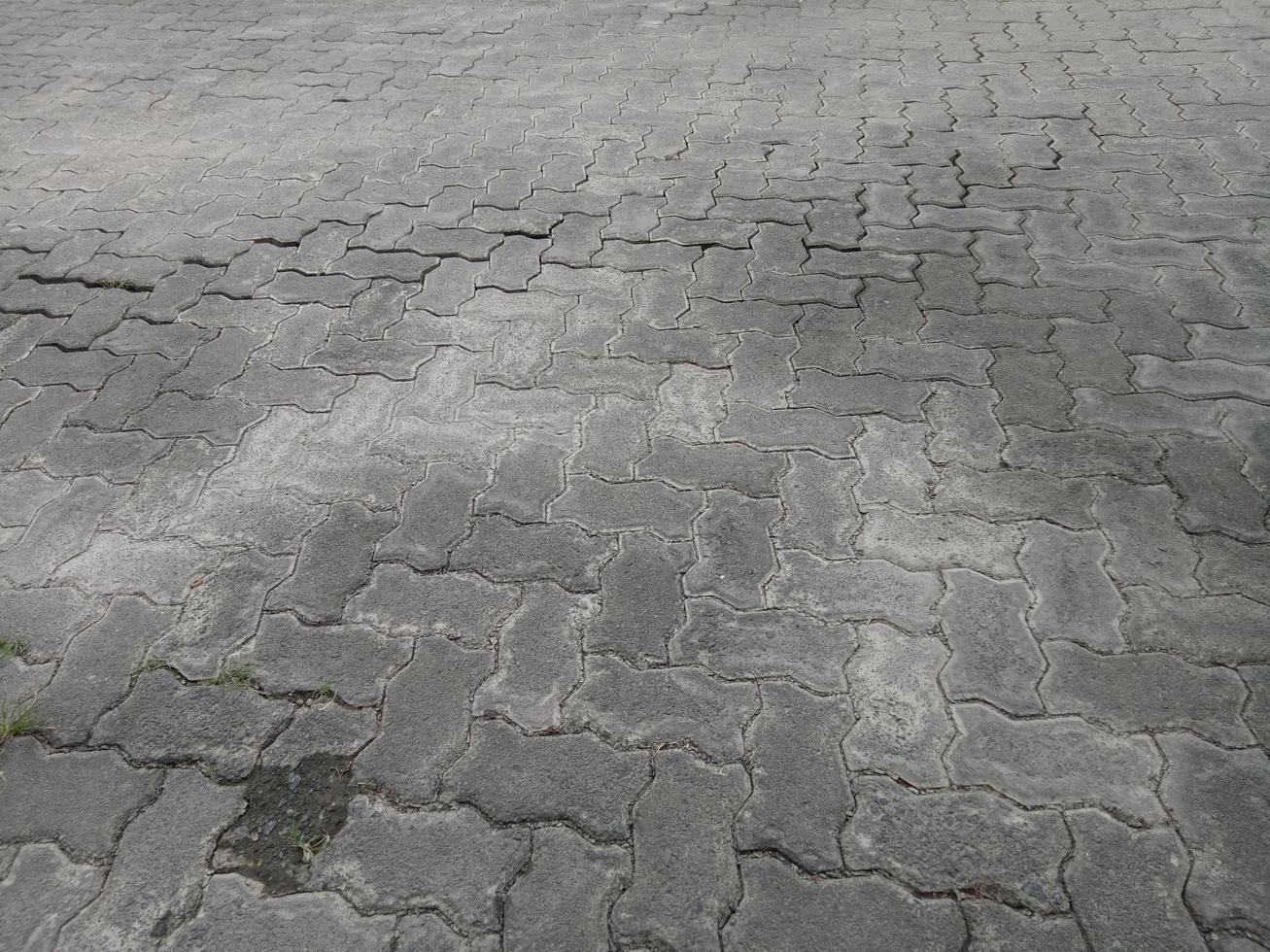 strade di pavimentazione in mattoni incrinate e sporche foto