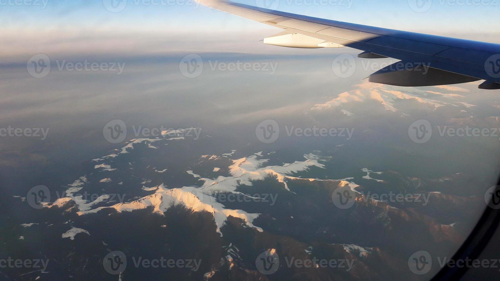 riprese aeree dalla finestra di un aereo sopra le montagne innevate. foto