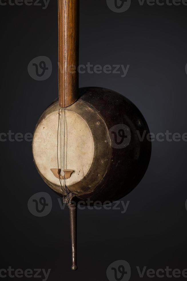 parte antico strumento musicale a corde asiatico su sfondo nero con retroilluminazione foto