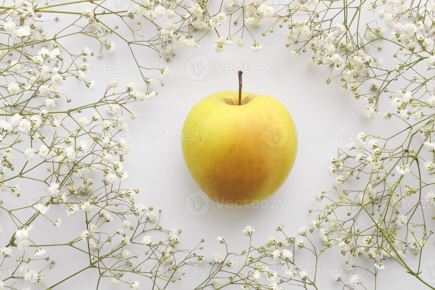bouquet di respiro del bambino o gipsofila e una mela gialla su sfondo bianco foto