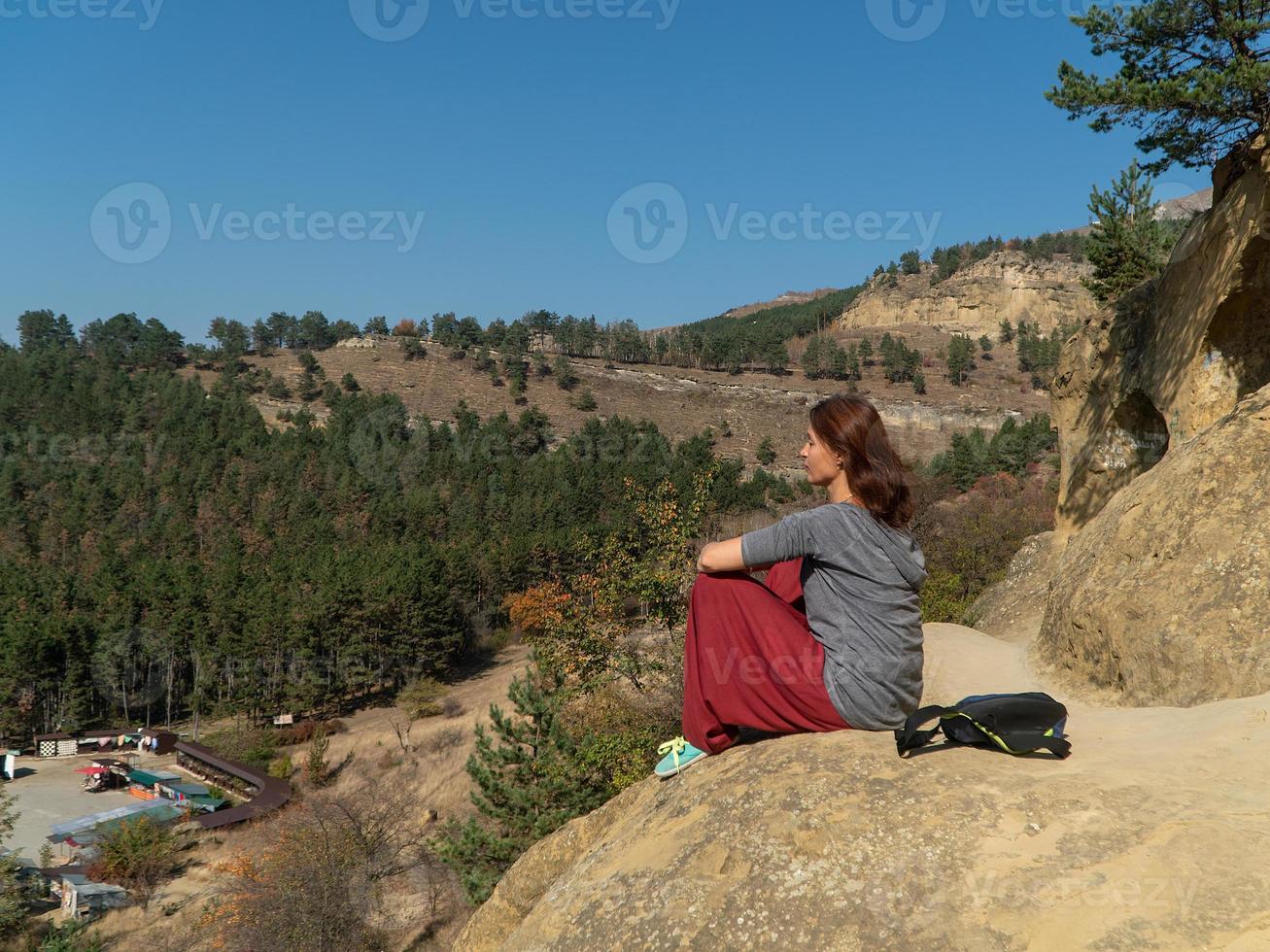 donna di fronte al sole su una montagna, vestita con pantaloni indiani, meditando, ritratto in una giornata autunnale foto