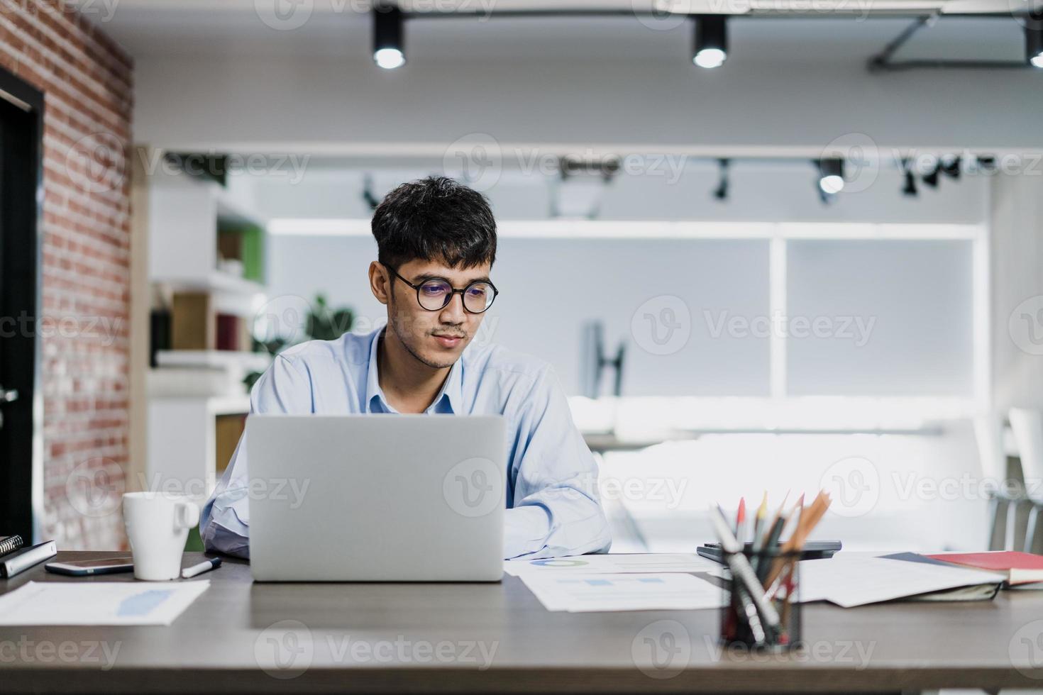 uomo creativo asiatico disegno piano di lavoro su cartone. giovane uomo d'affari professionale pensa e scrivi promemoria di informazioni su carta su mattone, situazione aziendale, avvio nel concetto di ufficio loft. foto